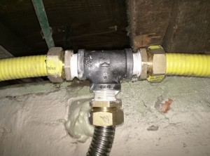 Three pieces of CSST come together at one traditional T-joint, where we split off a branch to feed the existing water heater.